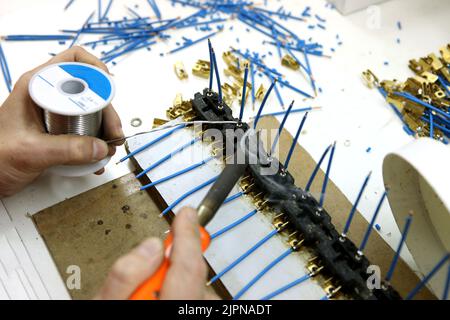 Un homme collecte une carte de circuit imprimé. Le travailleur souéquipe les composants de la radio et assemble le dispositif fini. Montage et commande manuels Banque D'Images