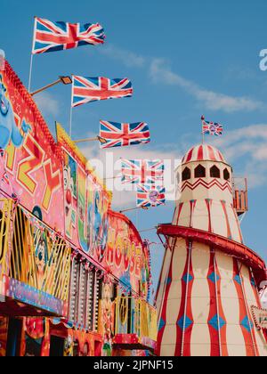 Un parc d'attractions/plage de loisirs haut en couleur en bord de mer avec un abri de squelettes et des drapeaux britanniques volant Hunstanton Norfolk Angleterre Royaume-Uni Banque D'Images