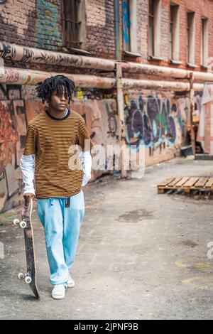 Jeune homme élégant noir avec des dreadlocks de cheveux naturels. Afroamerican Guy.Stairs, mur peint avec des graffitis dans le quartier pauvre de l'art de rue cultur Banque D'Images