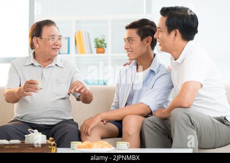 Homme âgé racontant des histoires à son fils et à son petit-fils Banque D'Images