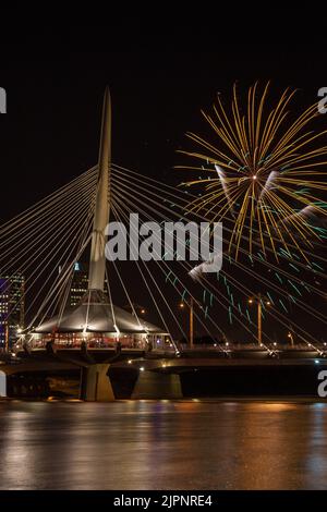 Un cliché vertical du pont de Provencher à Winnipeg avec des feux d'artifice dans le ciel Banque D'Images