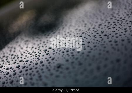 Cliché sélectif de gouttelettes d'eau noires sur une surface argentée sous un éclairage tamisé Banque D'Images