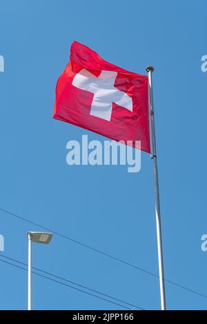 Truebbach, Suisse, 28 avril 2022 le drapeau national suisse agite dans le vent sur le pont du rhin à la frontière avec le Liechtenstein Banque D'Images