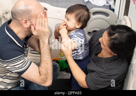 bébé garçon de 11 mois à la maison jouant peek a boo avec les parents Banque D'Images