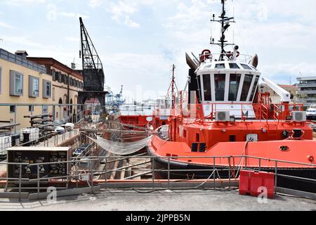 GÊNES, ITALIE - 14 AOÛT 2022 : un navire rouge dans un quai sec au chantier naval de Gênes, vu d'une zone piétonne publique. Banque D'Images