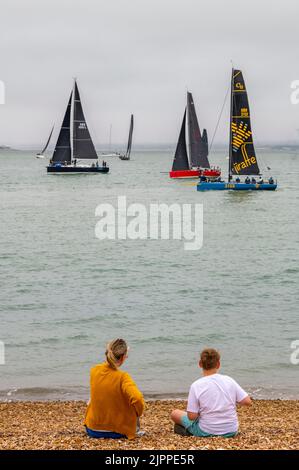 femme et garçon mère et fils regardant la course de yacht à la régate annuelle de la semaine des cowes sur l'île de wight, mère et fils sur la plage assis sur la plage Banque D'Images