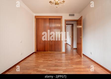 Chambre vide avec armoire intégrée avec portes coulissantes en bois, parquet en chêne français et menuiserie assortie. Banque D'Images