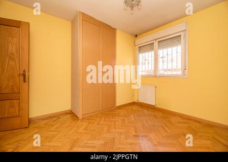 Chambre vide avec armoire intégrée avec portes en chêne pour s'harmoniser avec le parquet en chêne à chevrons Banque D'Images