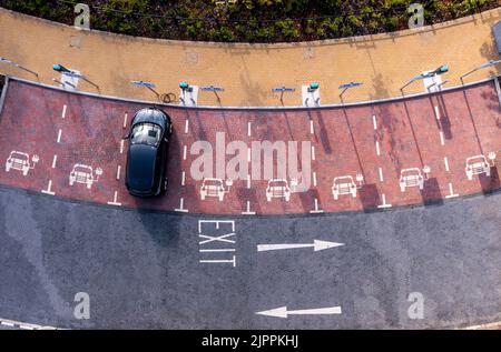 Une vue aérienne directement au-dessus d'un poste de charge de véhicule électrique avec chargement de voiture électrique dans une place de parking Banque D'Images