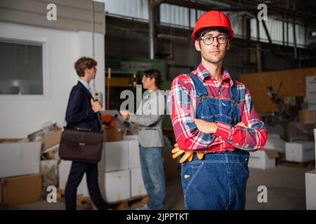 portrait d'un employé de l'usine avec des responsables en arrière-plan discutant Banque D'Images