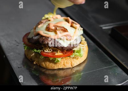 Gros plan sur la préparation d'un hamburger colombien dans un kiosque à nourriture. Pain, laitue, tomate, frites sur bâtonnets, viande de hamburger, Mozzarell Banque D'Images