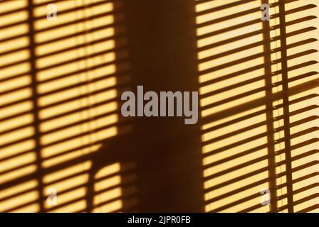 Ombres et lumière sur le mur provenant du soleil qui brille à travers les stores de fenêtre Banque D'Images