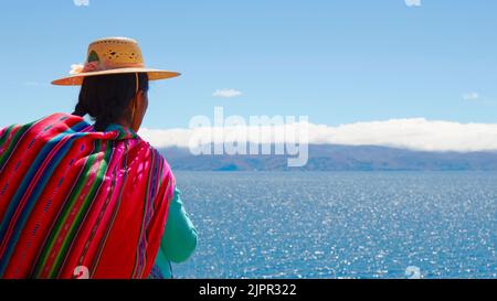 Femme bolivienne 'chola' vêtue de vêtements traditionnels colorés et regardant l'horizon sur 'Isla de la Luna' sur le lac Titicaca, province de la Paz, Bolivie. Banque D'Images