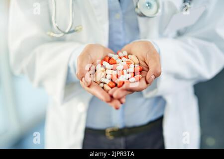 Pilules pour la prévention et la guérison. Gros plan d'un médecin non identifiable tenant une variété de pilules dans ses mains. Banque D'Images