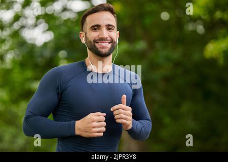 Courir est mon mode de vie. Portrait court d'un jeune homme charmant qui écoute de la musique pendant son entraînement. Banque D'Images