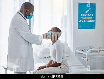 Médecin avec un patient dans un masque covid faisant l'examen de la thyroïde ou de la maladie de gorge pendant un examen médical, visite ou rendez-vous. Assurance Banque D'Images