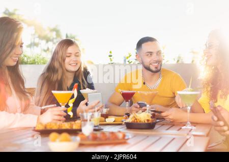 Groupe multiracial de jeunes amis s'amusant au restaurant, parlant et riant tout en dînant à table - style de vie et concepts d'amitié avec réel Banque D'Images