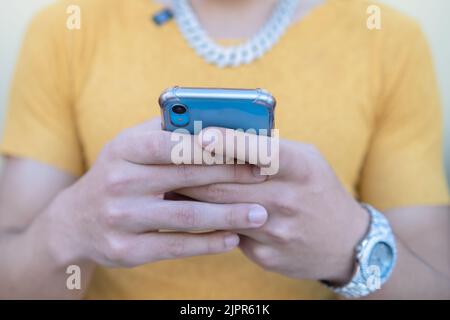 Gros plan sur un jeune homme heureux utilisant un smartphone moderne - un gars de taille basse saisissant un message sms sur le téléphone - Focus sélectif Banque D'Images