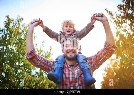 HES mon petit champion. Portrait à angle bas d'un beau jeune homme qui soutient son fils à l'extérieur pendant l'automne. Banque D'Images