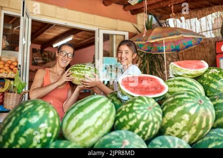 On dirait que les pastèques sont en saison. Portrait rogné d'une mère et d'une fille travaillant dans une ferme. Banque D'Images