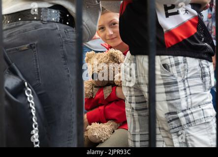 Une adolescente est assise sur une valise avec un grand ours en peluche entre adultes, attendant le train. Train d'évacuation de la dernière gare de Pokrovsk dans la région de Donetsk. Banque D'Images