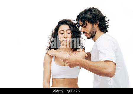 Ostéopathe d'homme faisant un traitement de lame d'épaule sur une jeune femme. Concept de soins du corps - isolé sur blanc - foyer sélectif Banque D'Images