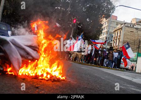 Valparaiso, Chili. 19th août 2022. Une bannière est mise sur le feu alors que des manifestants brandissaient des drapeaux chiliens lors d'une protestation contre une nouvelle constitution. Des manifestants s'empaissent dans les rues de Valparaiso pour rejeter une nouvelle constitution, certains contre-manifestants soutenant la nouvelle constitution de Valparaiso. Crédit : SOPA Images Limited/Alamy Live News Banque D'Images