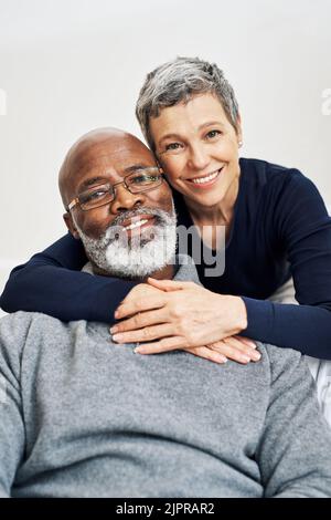 La meilleure vie est une vie passée avec votre soulmate. Portrait court d'un couple senior affectueux qui se détend sur le canapé à la maison. Banque D'Images