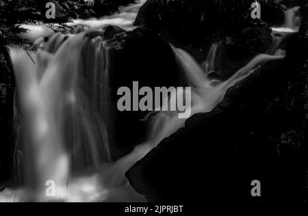 Chute d'eau tombant lentement du Gorgas del Alba dans la vallée de Benasque. Illumination de l'aube avec une lumière magique et ésotérique. Noir et blanc. Banque D'Images