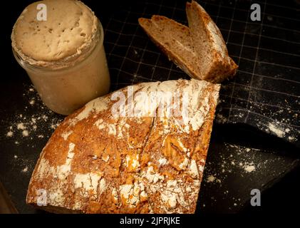 Pain de blé artisanal et de seigle avec farine graham. Entrée de levain sur fond sombre. Vue de dessus. Banque D'Images