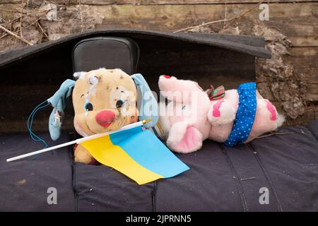 Un jouet sale cassé pour enfants et le drapeau de l'Ukraine se trouvent dans la cour pendant la guerre en Ukraine, la mort d'enfants aux mains du soldie russe Banque D'Images