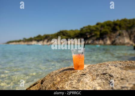 Femme sur la plage, buvant de la queue de cocon dans l'eau, appréciant l'été. Halkidiki, Grèce Banque D'Images
