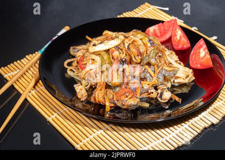 Nouilles Udon à la viande, aux champignons et aux légumes. Parsemé de graines de sésame. Cuisine asiatique, rôti sur fond noir, espace copie Banque D'Images