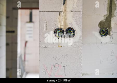 Nouveau mur vide de maison construit en AAC - béton cellulaire autoclavé, boîtes avec câbles pour prises électriques visibles Banque D'Images