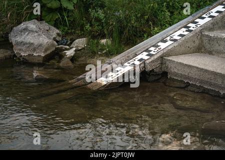 Échelle sur la rive de la rivière pour mesurer le niveau d'eau, qui est très bas sur cette photo Banque D'Images