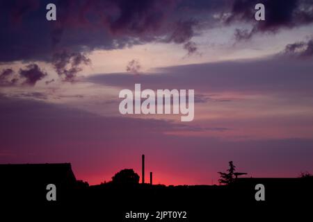 Superbes couleurs du ciel au coucher du soleil. Rose, violet ciel. Une image naturelle des couleurs du ciel. Silhouettes de bâtiments contre le ciel violet-rose. Banque D'Images