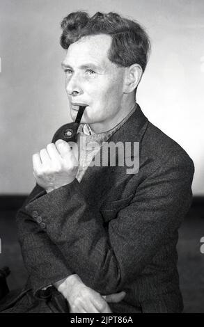 1950s, historique, fumeur de pipe, potrtrait d'un homme plus jeune, mi-30s; portant un chandail et une veste de sport assis pour sa photo, fumant son pipe, Angleterre, Royaume-Uni. Banque D'Images
