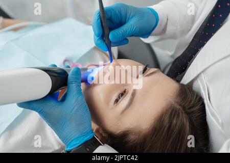 Gros plan d'une patiente en chaise dentaire sur une procédure d'examen numérique intrabuccal de ses dents. Scanner dentaire 3D moderne Banque D'Images