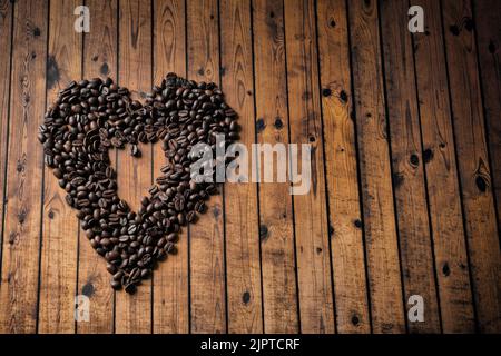 Forme de coeur en grains de café sur une surface en bois. Banque D'Images