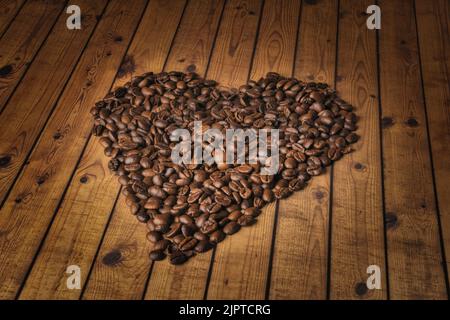 Forme de coeur en grains de café sur une surface en bois. Banque D'Images