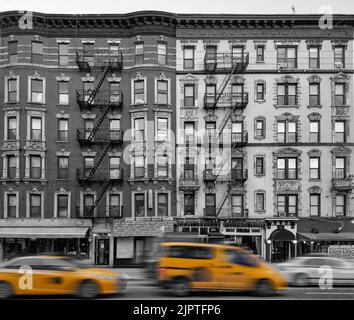 Taxis jaunes qui conduisent en noir et blanc devant de vieux immeubles d'appartements dans le quartier East Village de New York Banque D'Images