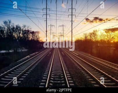 Les pistes de train convergent sur le paysage d'horizon avec la lumière colorée du coucher de soleil dans le ciel d'arrière-plan Banque D'Images