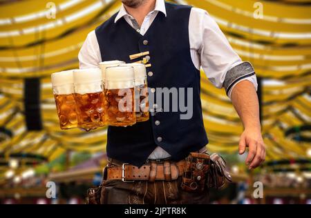 Oktoberfest, Munich. Serveur en costume bavarois traditionnel servant des bières, vue rapprochée. Fête d'octobre festival de la bière allemande. Banque D'Images