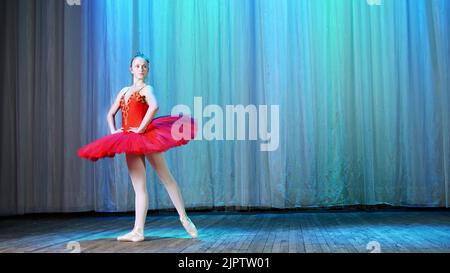 répétition de ballet, sur la scène de l'ancienne salle de théâtre. Ballerine jeune en rouge ballet tutu et Pointe chaussures, danse élégamment certain mouvement de ballet, sissone simple. Photo de haute qualité Banque D'Images