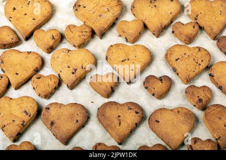 Biscuits en forme de coeur avec des gouttes de chocolat sur une plaque de cuisson Banque D'Images