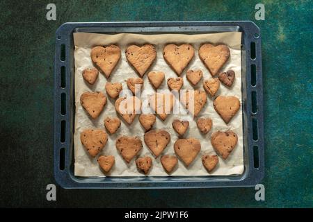 Biscuits en forme de coeur avec des gouttes de chocolat sur une plaque de cuisson Banque D'Images