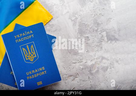 Sur fond gris clair, un drapeau ukrainien jaune-bleu, deux passeports biométriques ukrainiens. Il y a de l'espace libre à insérer. Voyage à l'étranger, tourisme, bu Banque D'Images