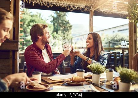 Un jeune couple affectueux qui toaste avec des sandwiches tout en savourant ses repas. Banque D'Images