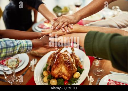 La nourriture est ce qui nous rassemble. Un groupe de personnes se empilant les mains à une table de salle à manger. Banque D'Images