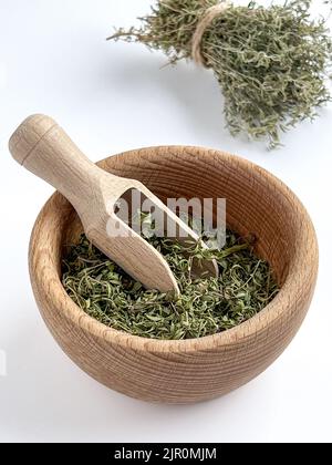 Feuilles de thym séchées dans un bol en bois sur fond blanc. Herbes pour la santé. Copier l'espace. Banque D'Images